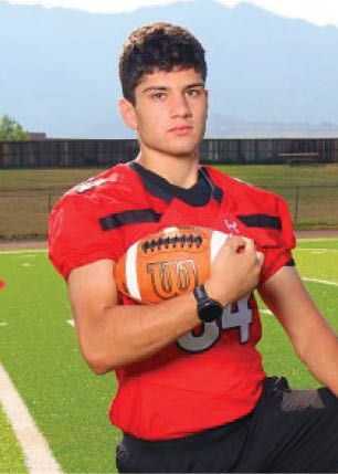 A young man wearing a white and black jersey with the number 14 on it. Description generated by AI