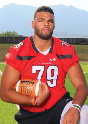 A young man wearing a white and black jersey with the number 14 on it. Description generated by AI
