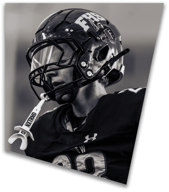 A person wearing a dark football uniform and helmet with “American Canyon" on the jersey is kneeling on one knee on a field at night. Description generated by AI