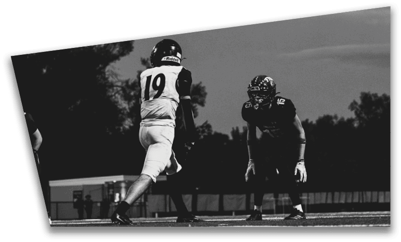 People wearing black American Canyon football uniforms and helmets are standing on a football field at night. Description generated by AI
