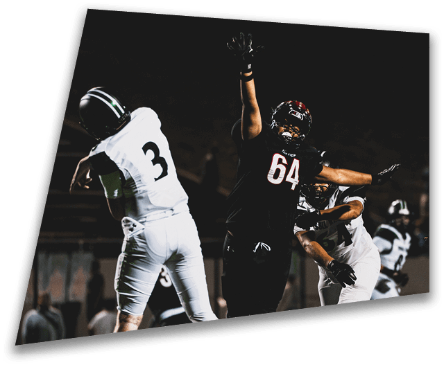 Four people in dark football uniforms and helmets stand in a row on a field, appearing focused and ready for action. Description generated by AI