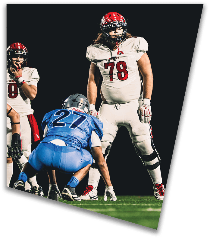 A person wearing a dark football uniform and helmet with “American Canyon" on the jersey is kneeling on one knee on a field at night. Description generated by AI