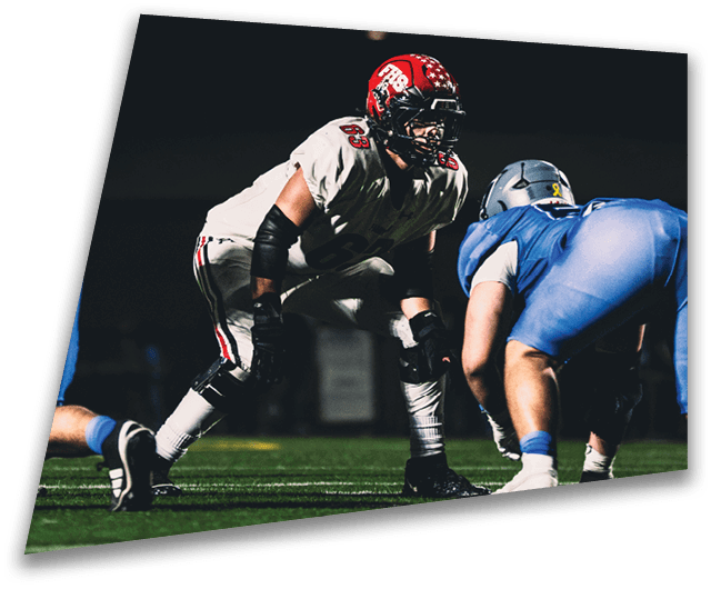 Four people in dark football uniforms and helmets stand in a row on a field, appearing focused and ready for action. Description generated by AI