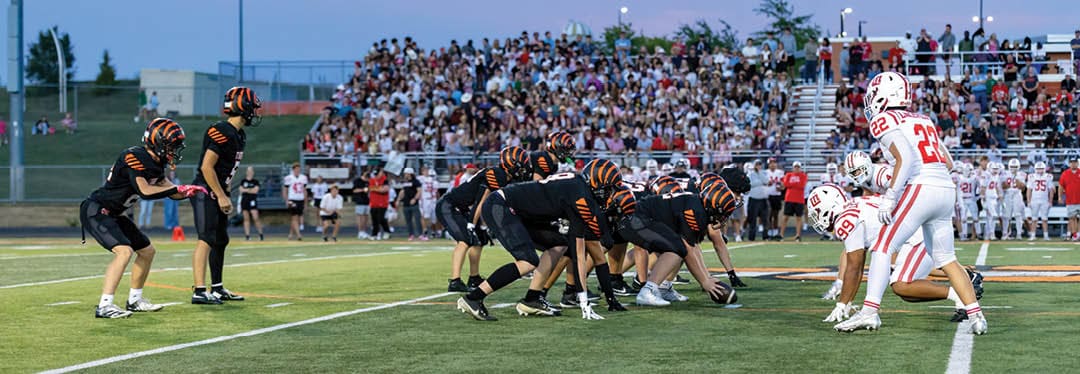 Four people wearing black sports jerseys with “VISTA" on them stand closely together in front of a large crowd, with one person raising an arm in celebration. Description generated by AI