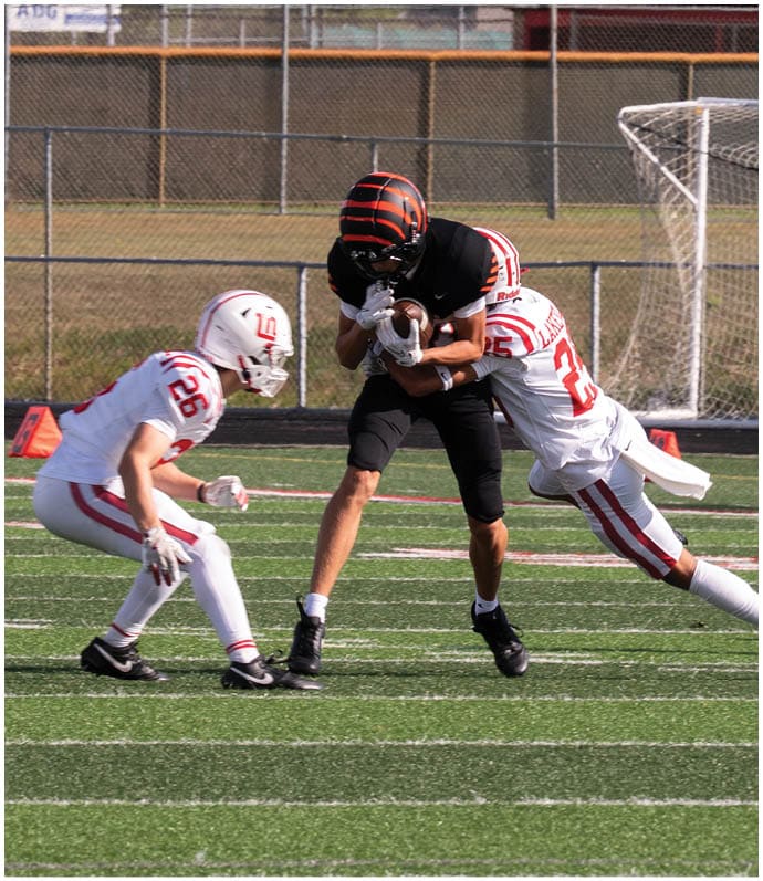 Three football players in blue and white uniforms running on a field. Description generated by AI