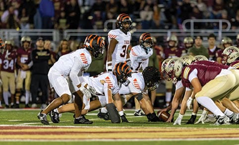 Two men wearing football uniforms are hugging each other on a field. AI generated content
