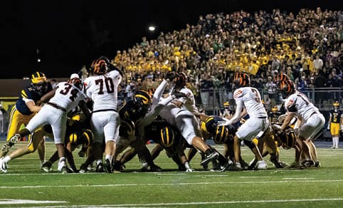 Two men wearing football uniforms are hugging each other on a field. AI generated content