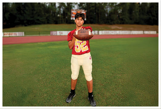 A football player wearing a blue and red jersey. Description generated by AI