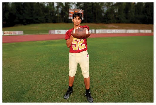 A football player wearing a blue and red jersey. Description generated by AI