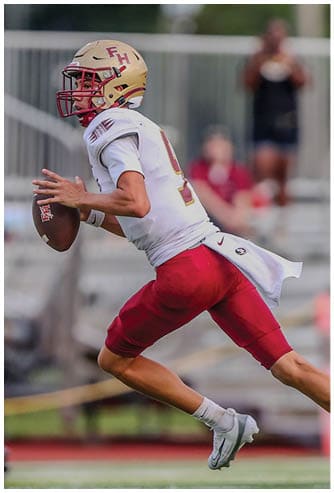 A person wearing a football helmet and uniform is running while holding a football, preparing to throw it. Description generated by AI