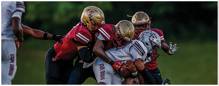 Two football players in helmets and uniforms are positioned on a field under stadium lights during a game. Description generated by AI
