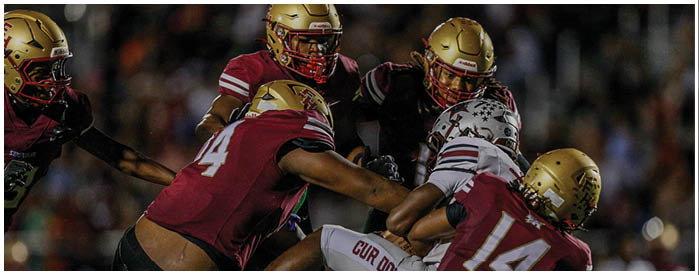 Two football players in helmets and uniforms are positioned on a field under stadium lights during a game. Description generated by AI