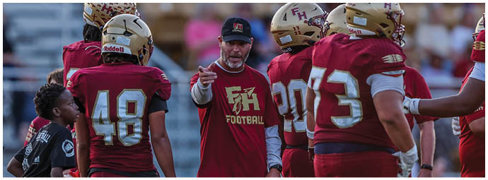 Several people wearing sports uniforms and standing on a field appear to be engaged in a discussion or preparing for a game. Description generated by AI