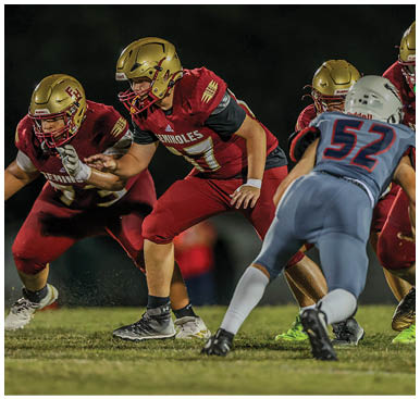 A person wearing a red football uniform with the word Seminoles and the number 17 is crouched in an athletic stance on a dark field. Description generated by AI