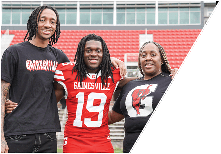 Three people stand side by side with their arms around each other, one wearing a red sports uniform with the number 19. Description generated by AI