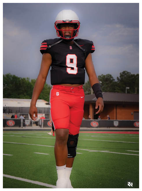 Two football players wearing black jerseys and holding hands. Description generated by AI