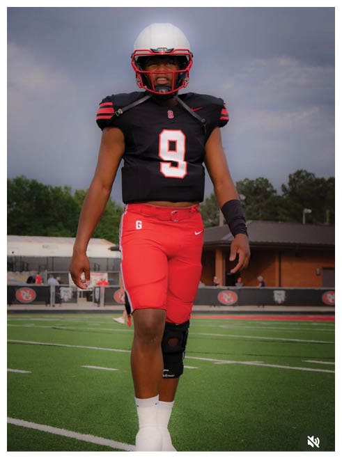 Two football players wearing black jerseys and holding hands. Description generated by AI