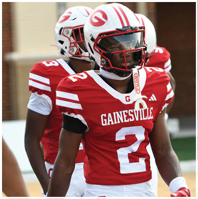 Two people wearing red and white football uniforms and helmets are standing side by side. Description generated by AI