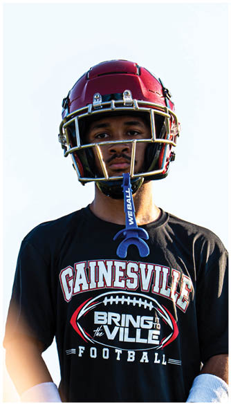 A person wearing a red football helmet is partially visible at the bottom of the image against a plain light background. Description generated by AI