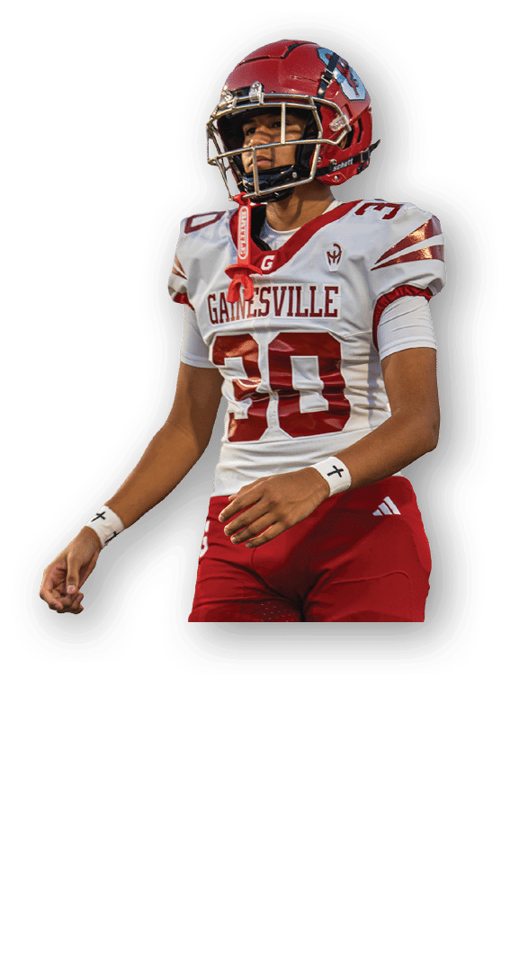 A person wearing a red and white Gainesville football uniform and helmet stands on a field with a focused expression. Description generated by AI