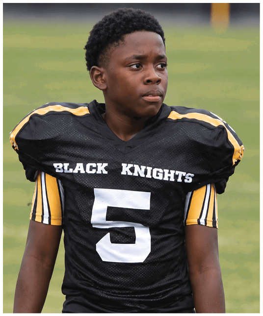 A person wearing a black sports jersey with yellow and white stripes and the words “BLACK KNIGHTS" printed on the front. Description generated by AI