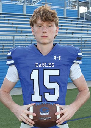 A young man wearing a white and black jersey with the number 14 on it. Description generated by AI
