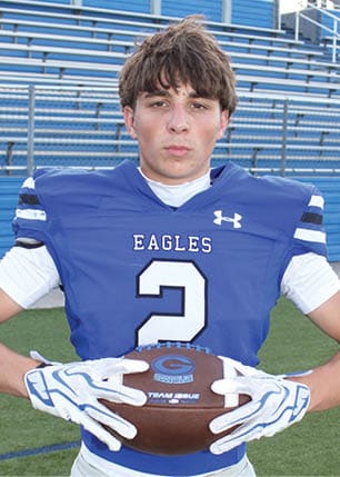 A young man wearing a white and black jersey with the number 14 on it. Description generated by AI