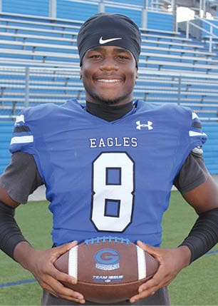 A young man wearing a white and black jersey with the number 14 on it. Description generated by AI