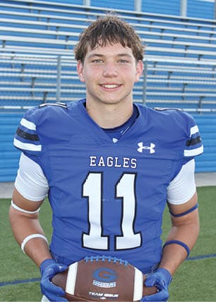 A young man wearing a white and black jersey with the number 14 on it. Description generated by AI