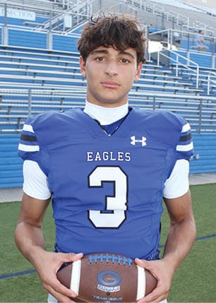 A young man wearing a white and black jersey with the number 14 on it. Description generated by AI