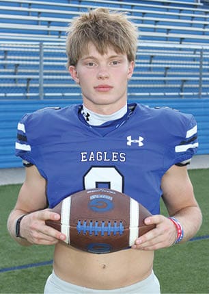 A young man wearing a white and black jersey with the number 14 on it. Description generated by AI