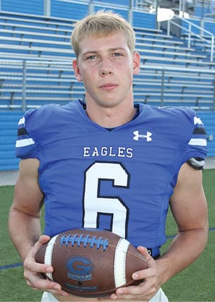 A young man wearing a white and black jersey with the number 14 on it. Description generated by AI