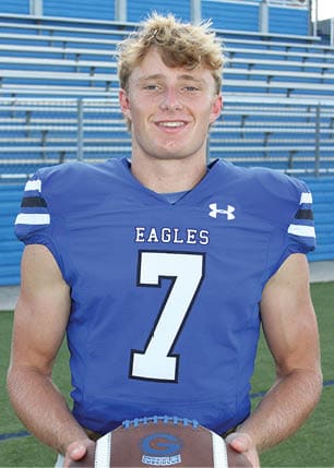 A young man wearing a white and black jersey with the number 14 on it. Description generated by AI
