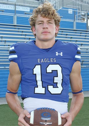 A young man wearing a white and black jersey with the number 14 on it. Description generated by AI