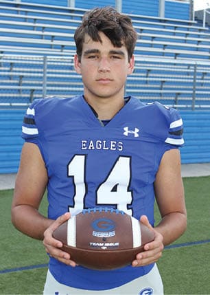 A young man wearing a white and black jersey with the number 14 on it. Description generated by AI