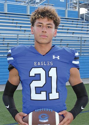 A young man wearing a white and black jersey with the number 14 on it. Description generated by AI