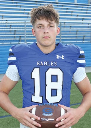 A young man wearing a white and black jersey with the number 14 on it. Description generated by AI
