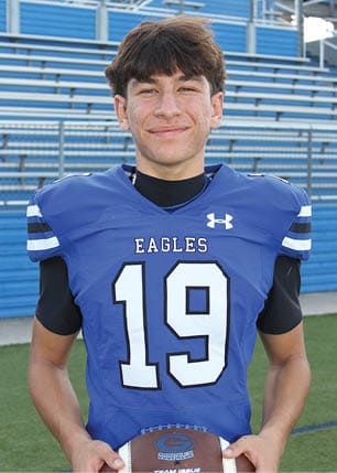 A young man wearing a white and black jersey with the number 14 on it. Description generated by AI