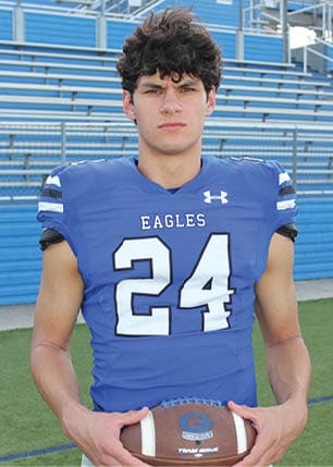 A young man wearing a white and black jersey with the number 14 on it. Description generated by AI