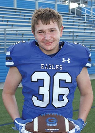 A young man wearing a white and black jersey with the number 14 on it. Description generated by AI