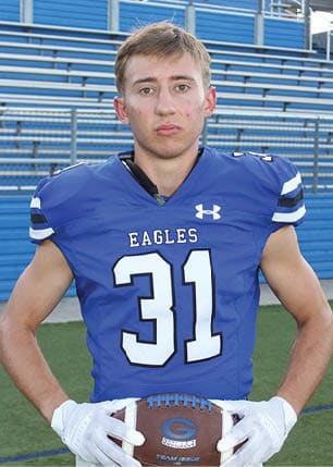 A young man wearing a white and black jersey with the number 14 on it. Description generated by AI