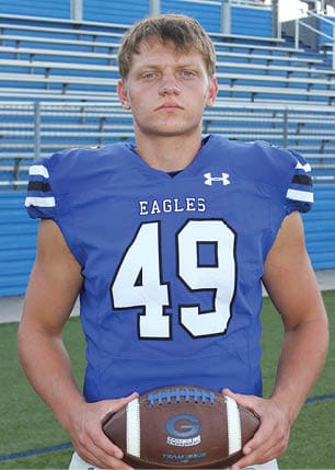 A young man wearing a white and black jersey with the number 14 on it. Description generated by AI