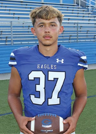 A young man wearing a white and black jersey with the number 14 on it. Description generated by AI