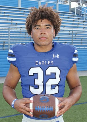 A young man wearing a white and black jersey with the number 14 on it. Description generated by AI