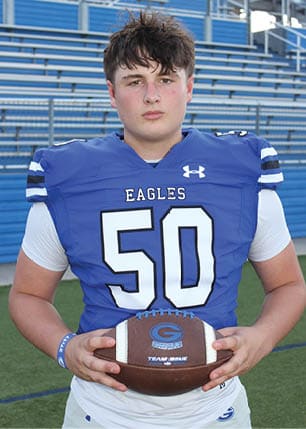 A young man wearing a white and black jersey with the number 14 on it. Description generated by AI