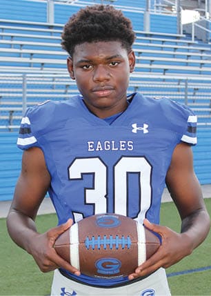 A young man wearing a white and black jersey with the number 14 on it. Description generated by AI
