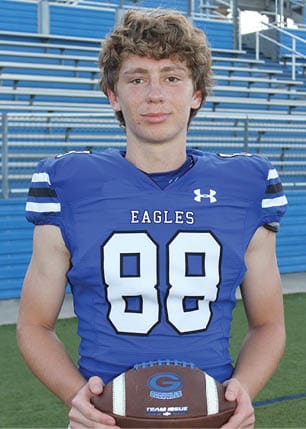A young man wearing a white and black jersey with the number 14 on it. Description generated by AI