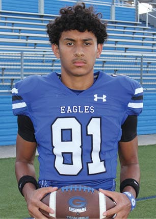 A young man wearing a white and black jersey with the number 14 on it. Description generated by AI