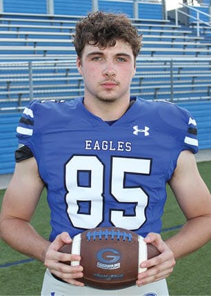 A young man wearing a white and black jersey with the number 14 on it. Description generated by AI