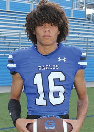 A young man wearing a white and black jersey with the number 14 on it. Description generated by AI